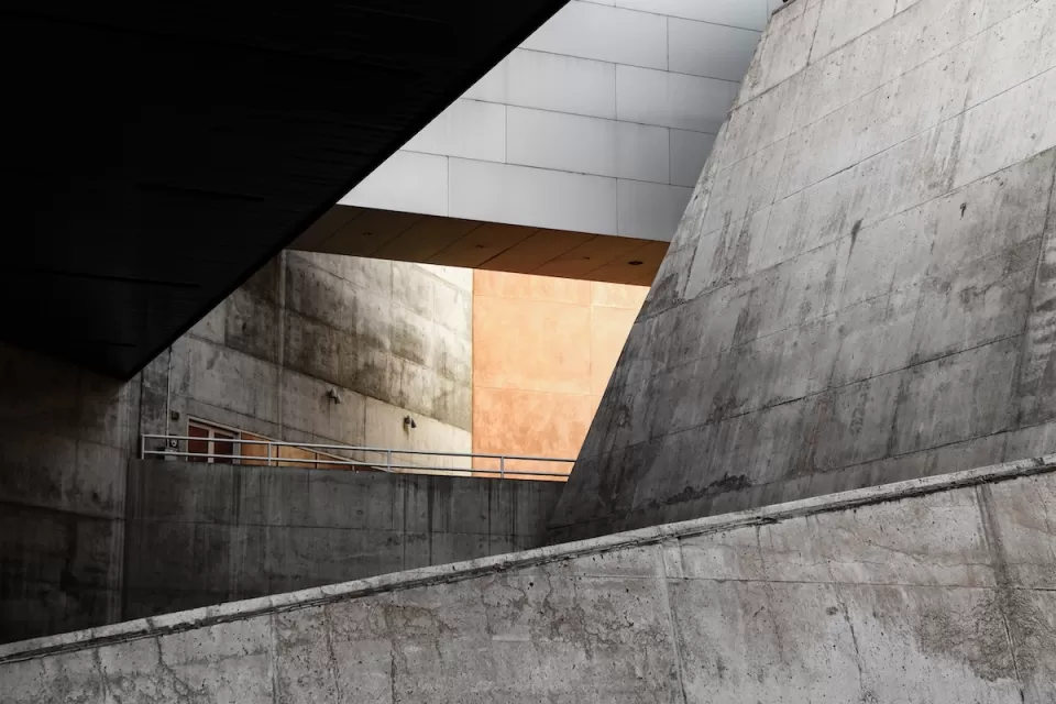 Concrete Brutalism building with slanted walls and light visible through an atrium.